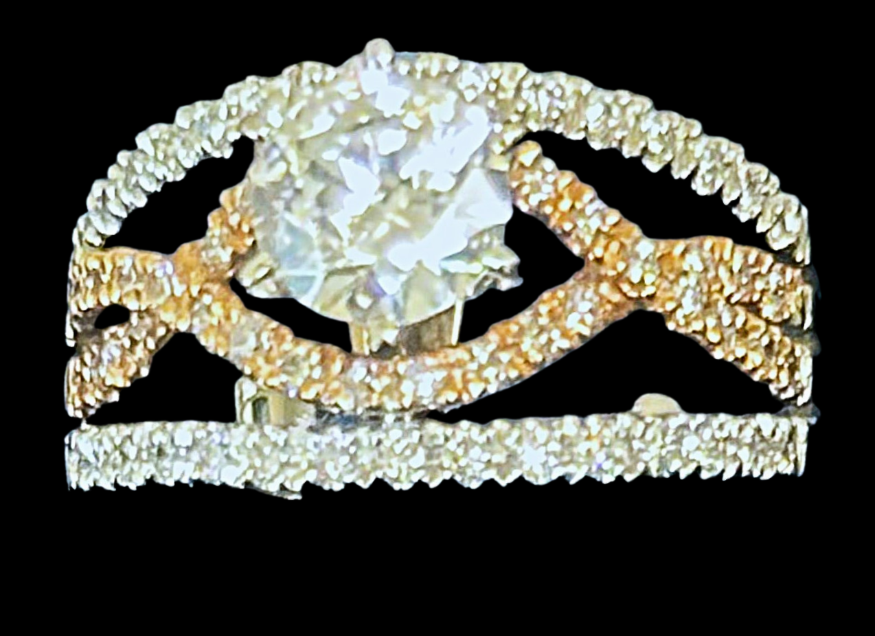 Diamond ring with intricate gold and silver bands, set against a black background.