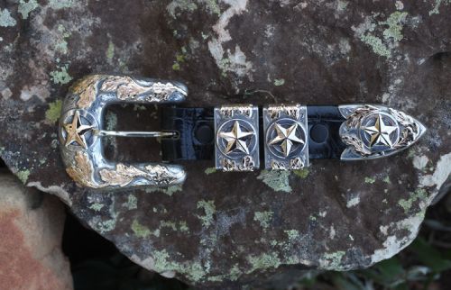Silver and gold belt buckle set with star design on a rock.