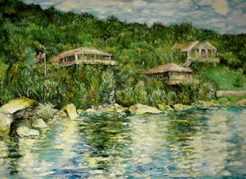 Houses on a hillside by water, green trees, cloudy sky, water reflections.