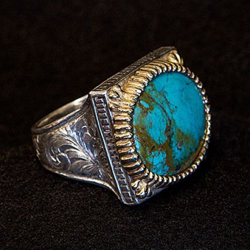 Silver ring with a large turquoise stone, set on a dark background.