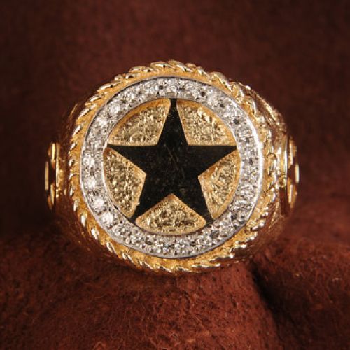 Gold ring with black star, surrounded by diamonds and rope-like detail.