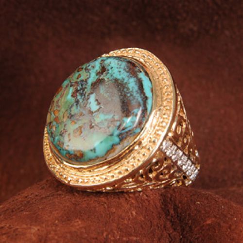 Gold ring with large turquoise stone and diamond accents on a brown background.