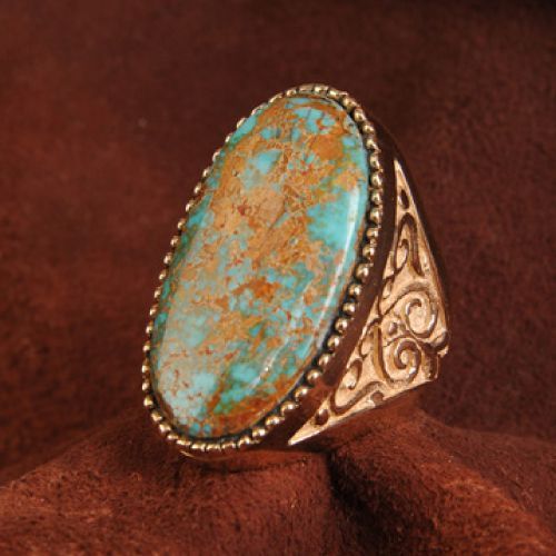 Gold ring with large oval turquoise stone and decorative side details.
