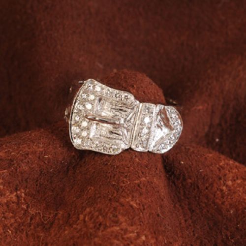 Diamond ring, silver setting, rectangular and triangular stones, on a brown fabric.