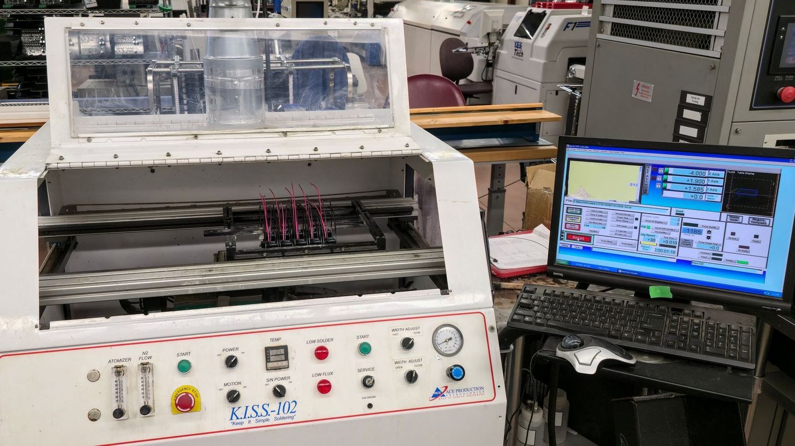A computer monitor is sitting next to a machine in a factory.