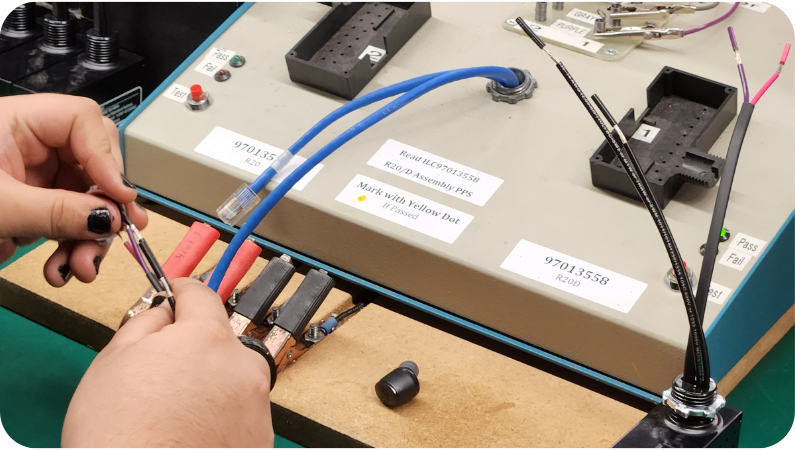 A person is working on a circuit board with wires connected to it.