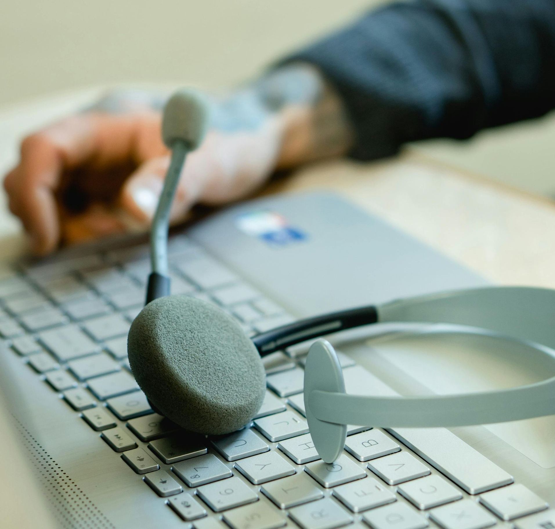 A person wearing a headset is typing on a laptop