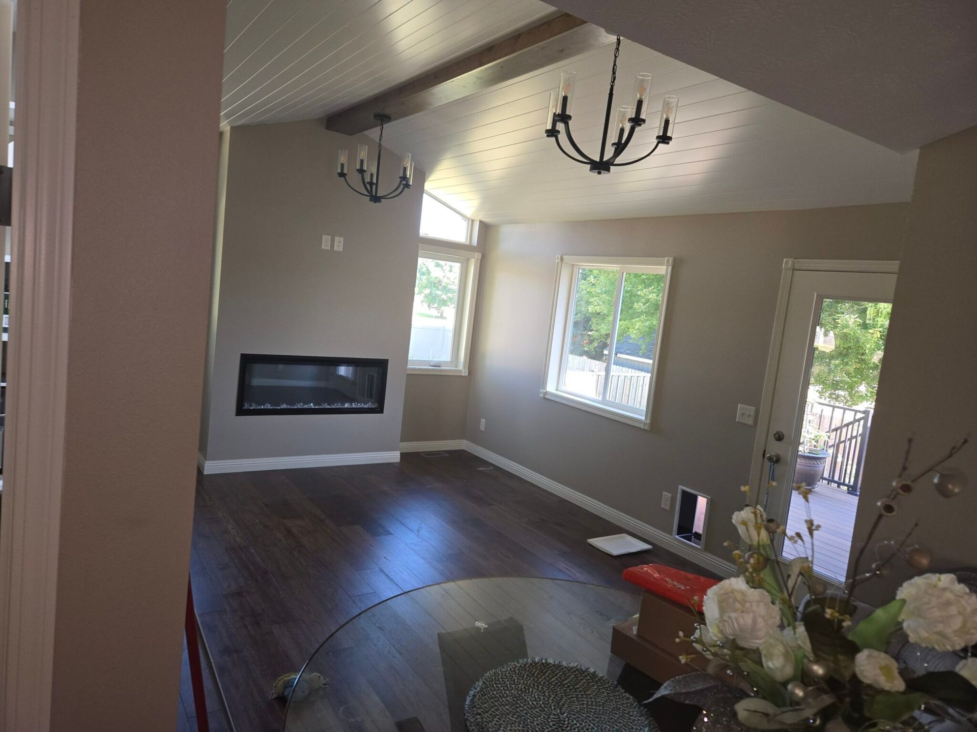 Living room with dark wood floors, fireplace, and two chandeliers.