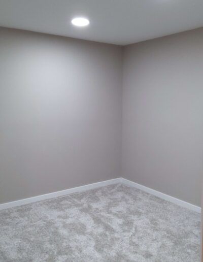 Empty room with light gray walls, white baseboards, and light gray carpet. A recessed ceiling light.