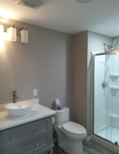 Bathroom with gray walls, vanity with a white vessel sink, and a glass shower.
