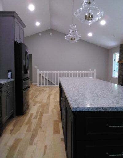 Kitchen with dark cabinets, light wood floor, gray walls, and a white granite island countertop.