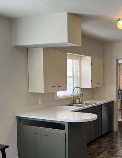 Kitchen with white countertop, cabinets, and a sink.  A soffit extends from the cabinets.