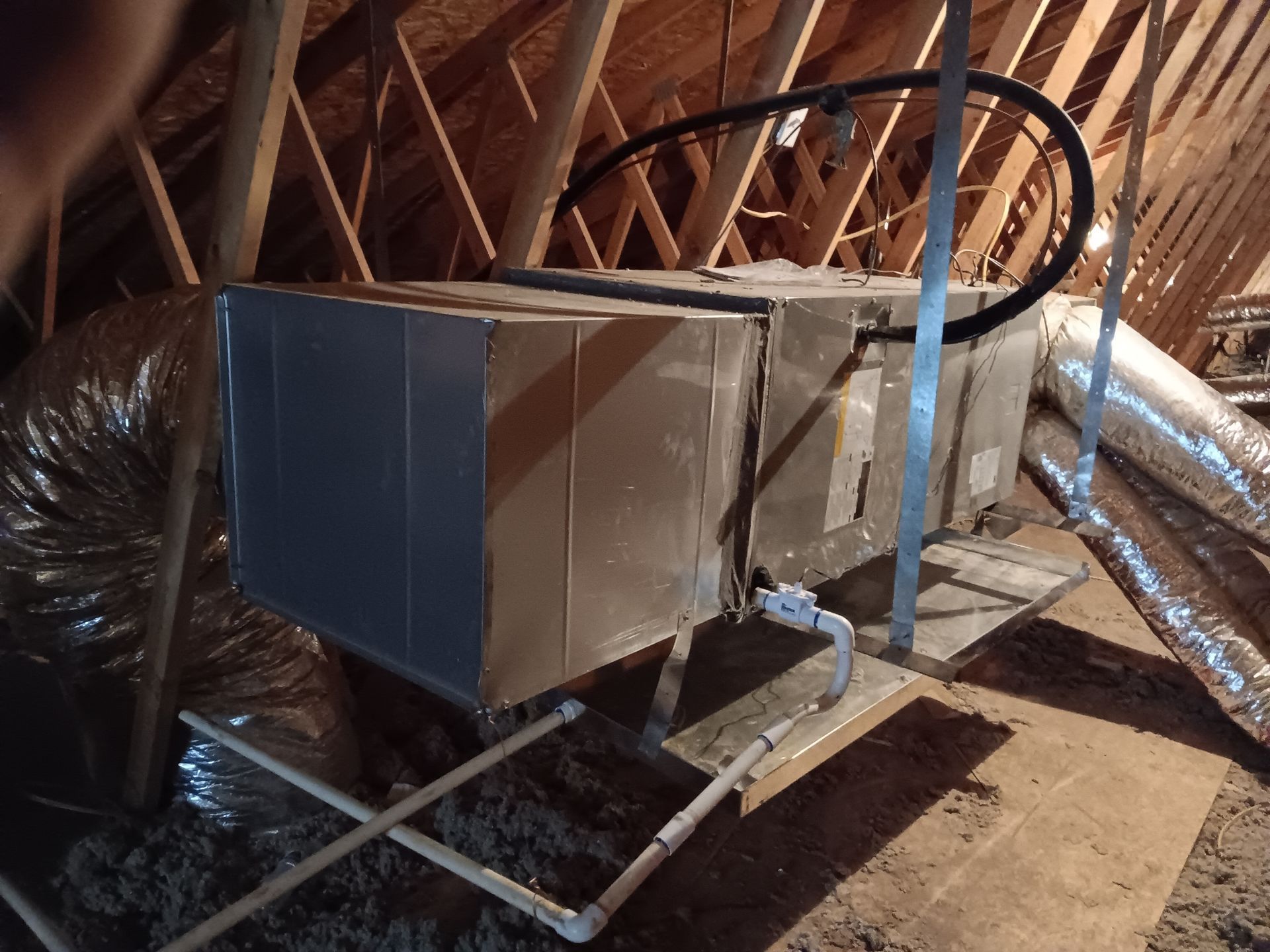 An air conditioner is sitting in the attic of a house.