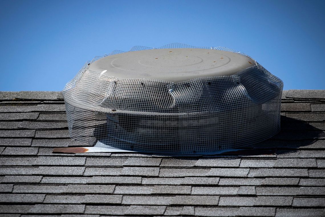 A round object is wrapped in plastic and sitting on top of a roof.