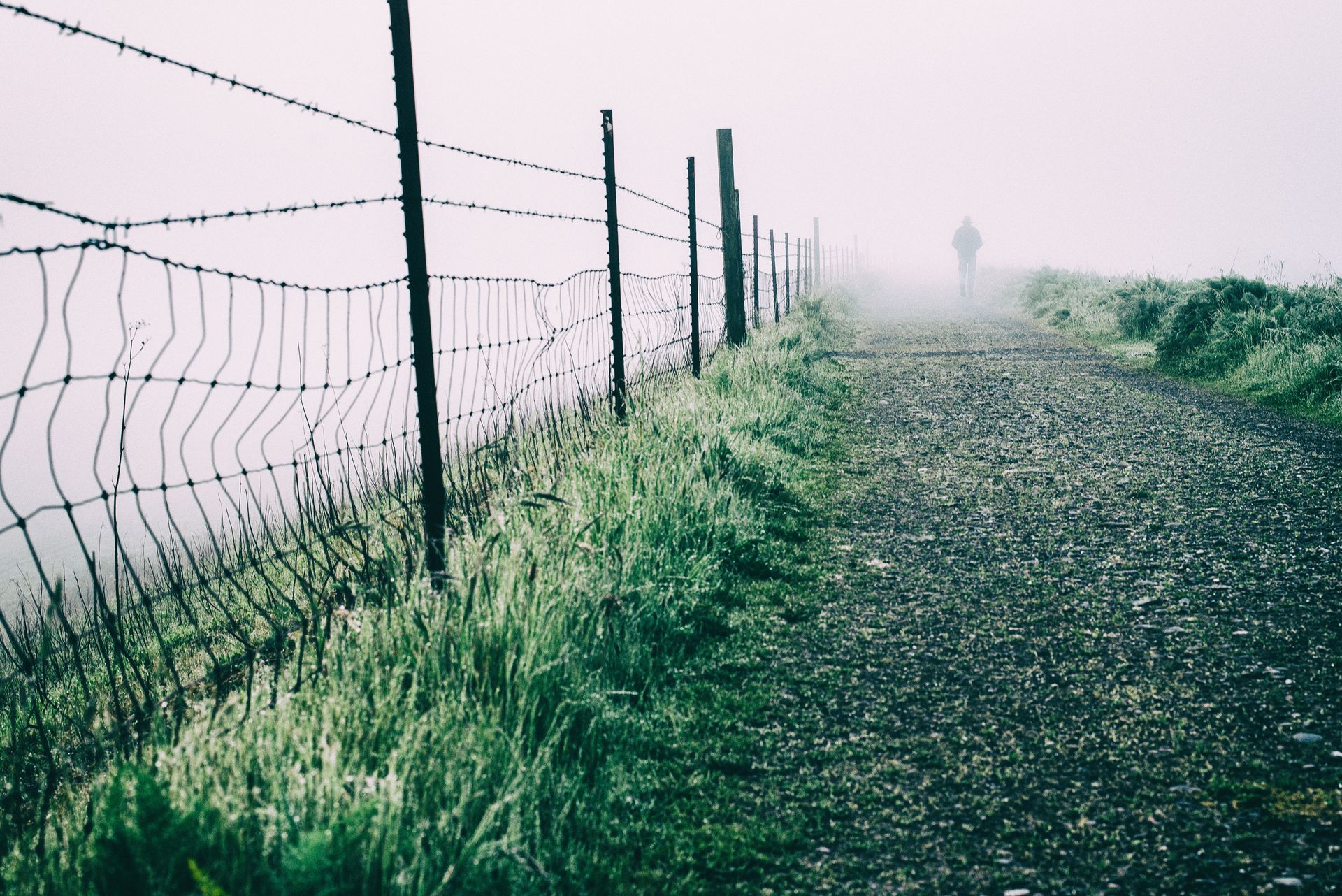 A dream catcher is hanging on a wire fence.