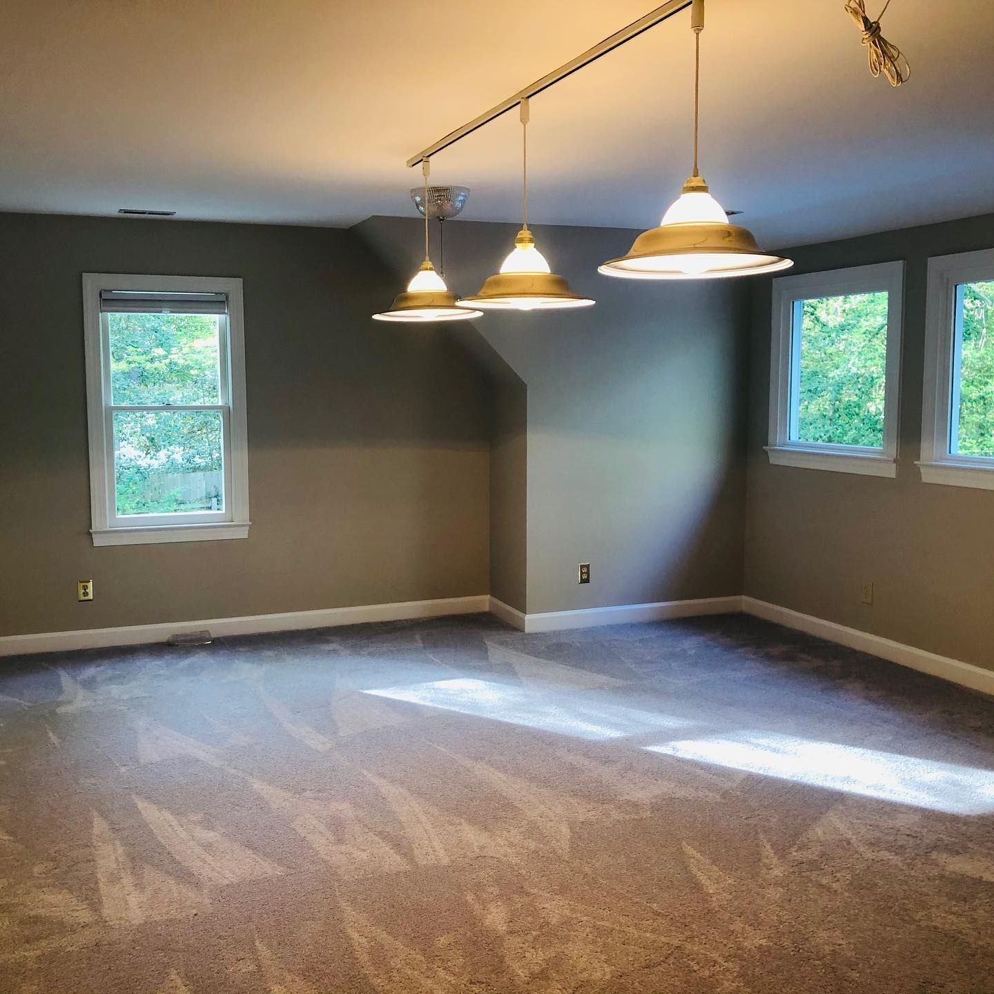 White kitchen with cabinets, island, and overhead lighting. A nearby doorway leads to a bathroom. White kitchen with cabinets, island, and overhead lighting. A nearby doorway leads to a bathroom.