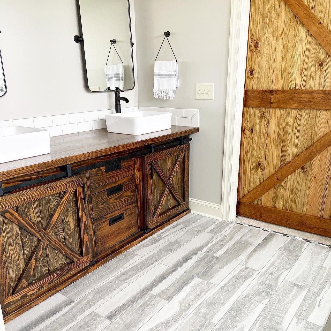 Bathroom with wooden vanity, barn door, and gray flooring. Bathroom with wooden vanity, barn door, and gray flooring.