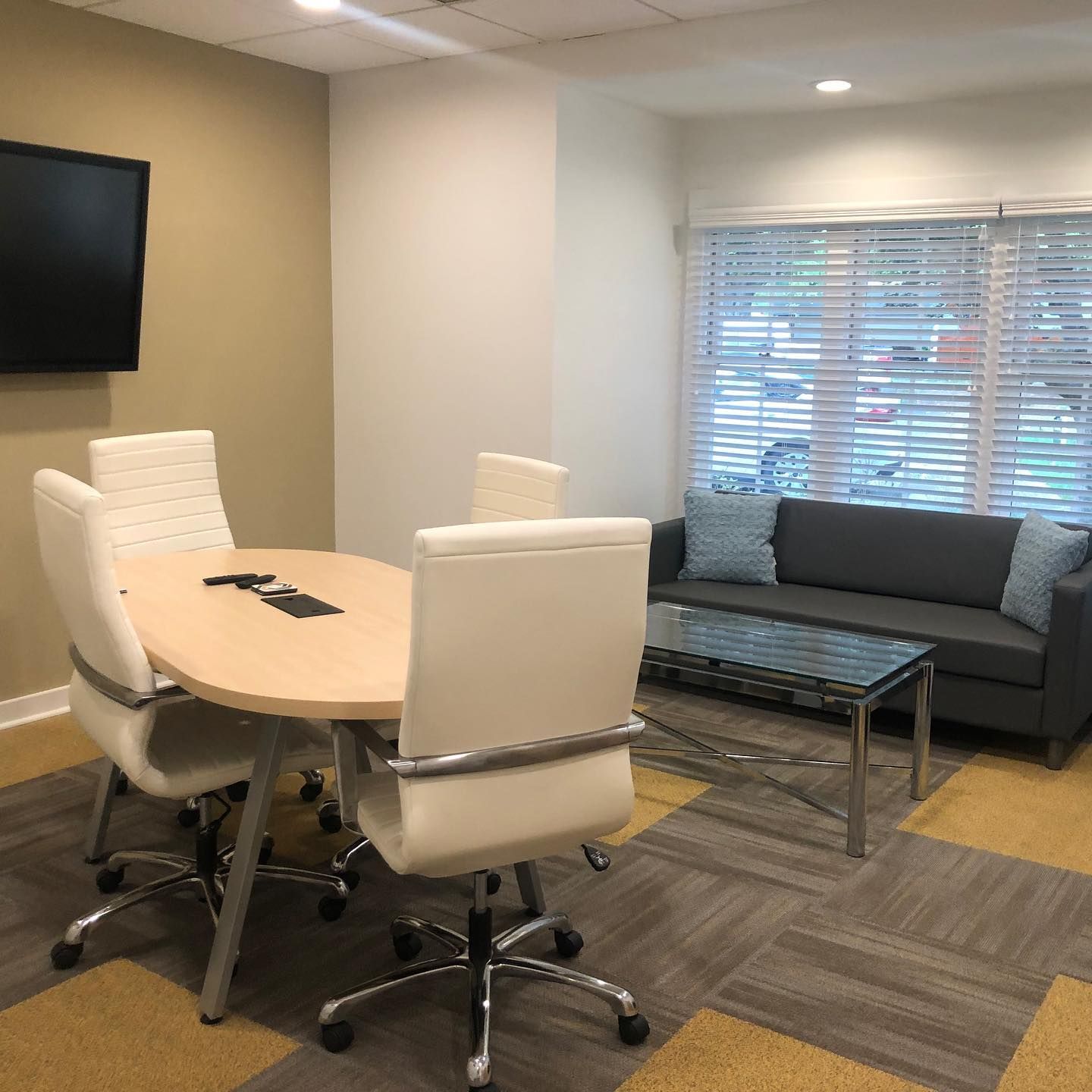 Meeting room with a table, chairs, TV, couch, and window with blinds. Meeting room with a table, chairs, TV, couch, and window with blinds.