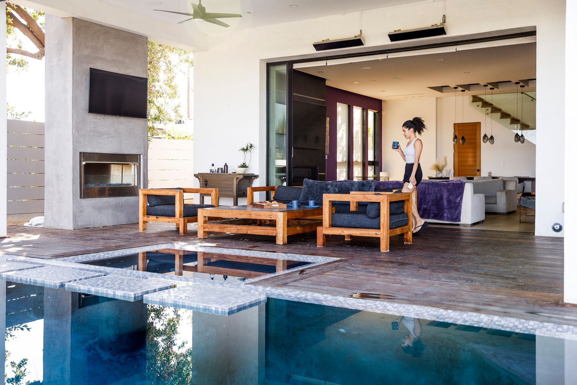 Patio with stone paving, outdoor furniture, and a house with green siding. Sunny day.