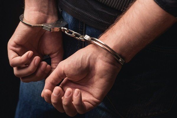 Young Criminal Standing In Handcuffs — Tulare County, CA — Perez Law Firm