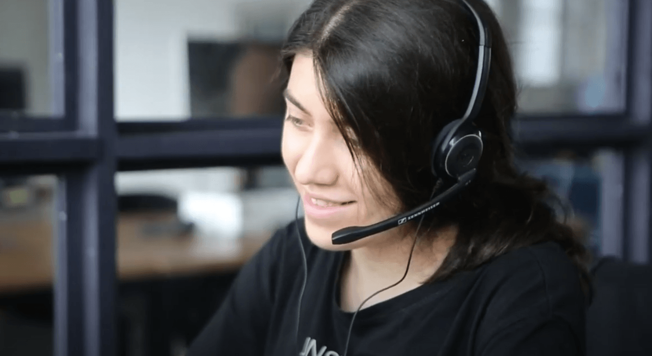 A woman is wearing a headset while sitting at a desk.