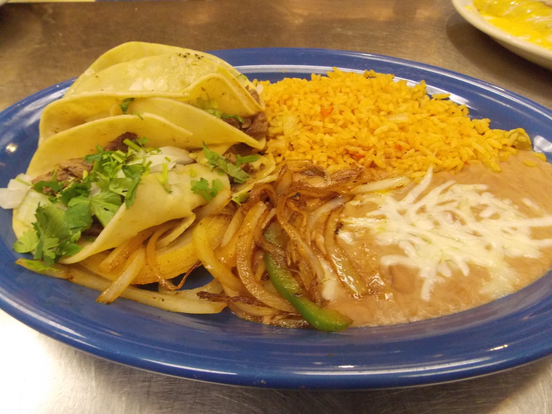 A blue plate topped with tacos rice and beans