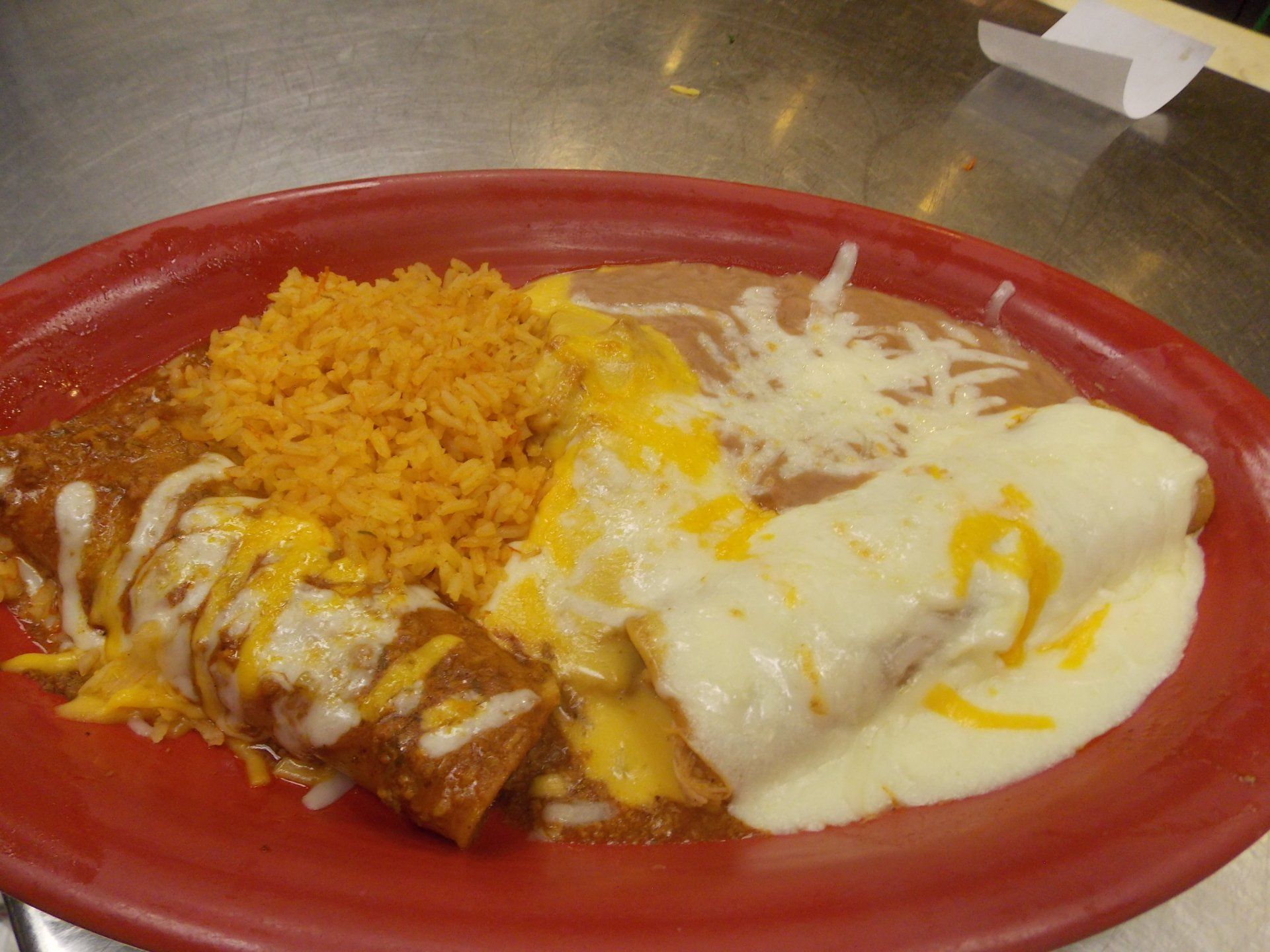 A plate of mexican food with rice and cheese on a table.