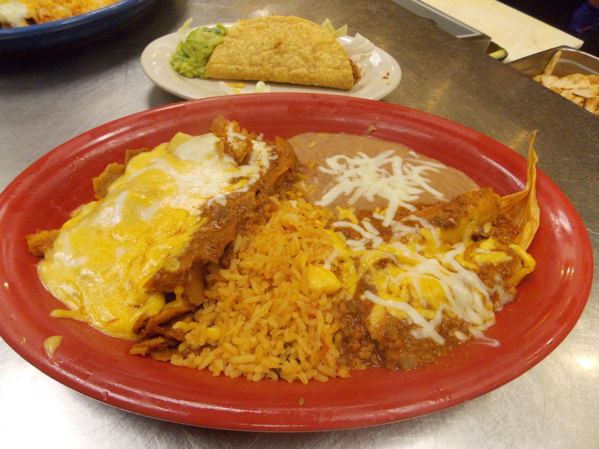 A plate of mexican food with rice and cheese on a table