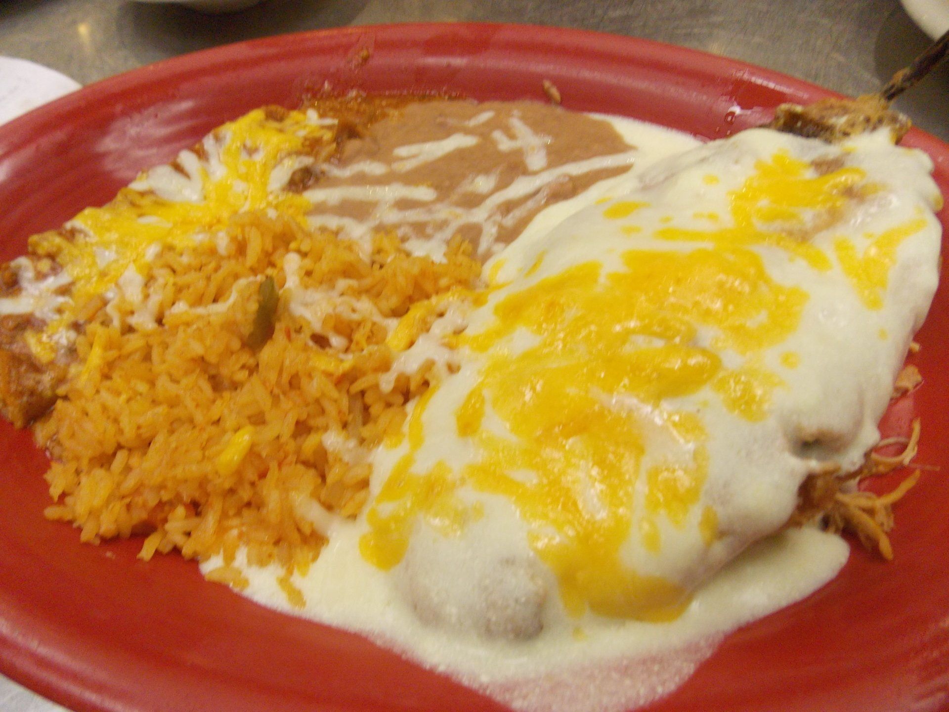 A close up of a plate of food with rice and cheese on a table.