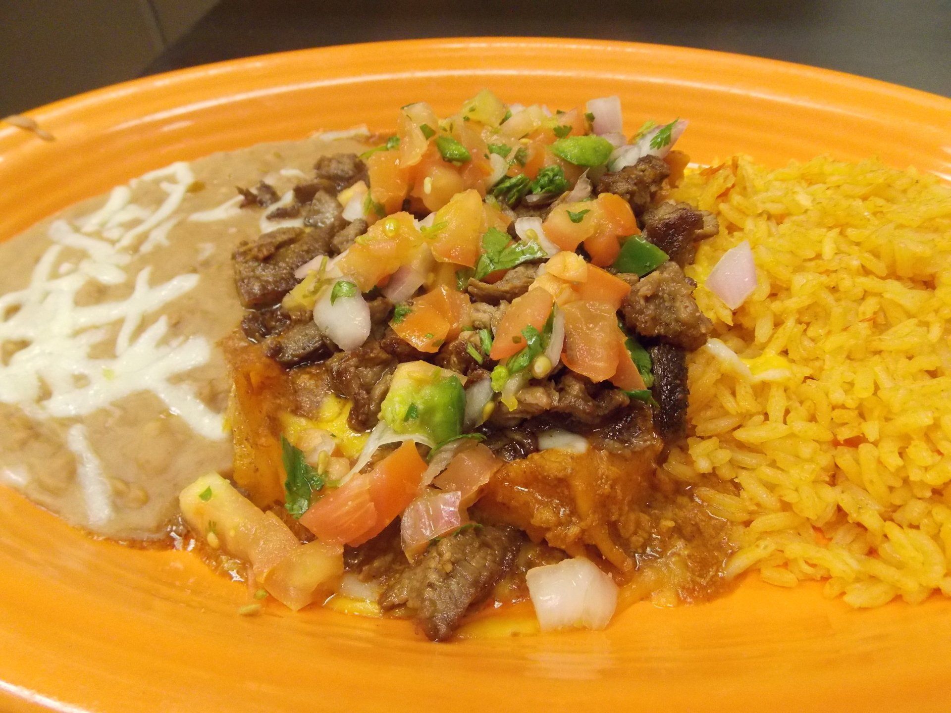 A close up of a plate of food with rice and beans on a table.