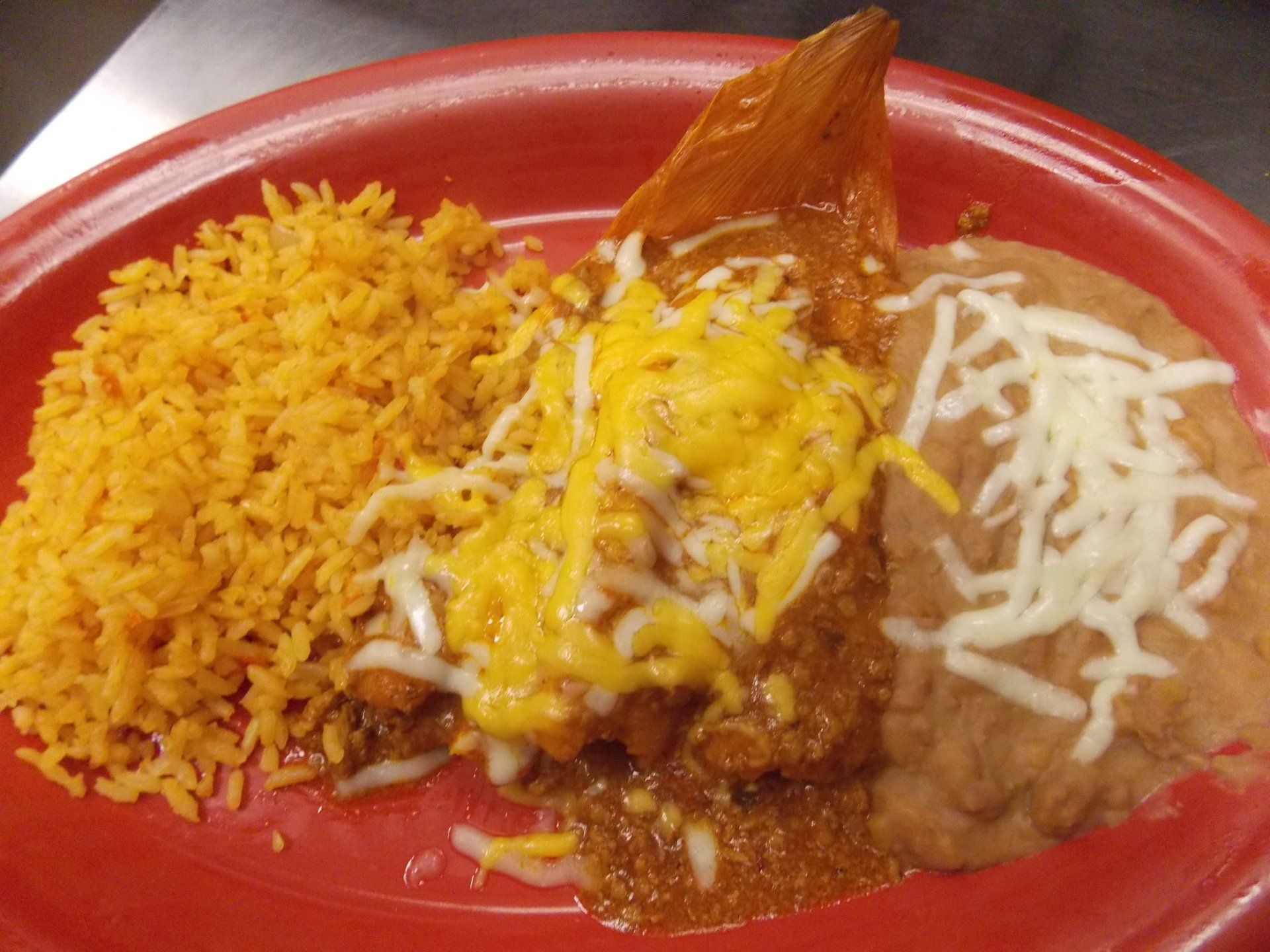 A red plate topped with rice beans and cheese