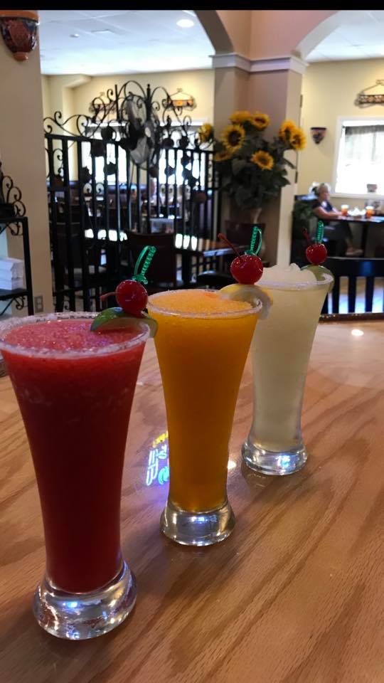 Three smoothies are sitting on a wooden table in a restaurant.