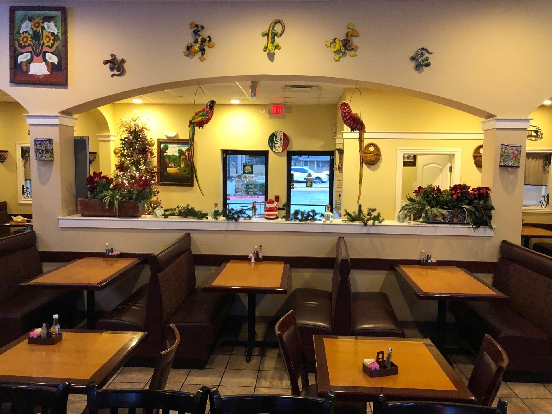 A restaurant with tables and chairs and a christmas tree on the wall.