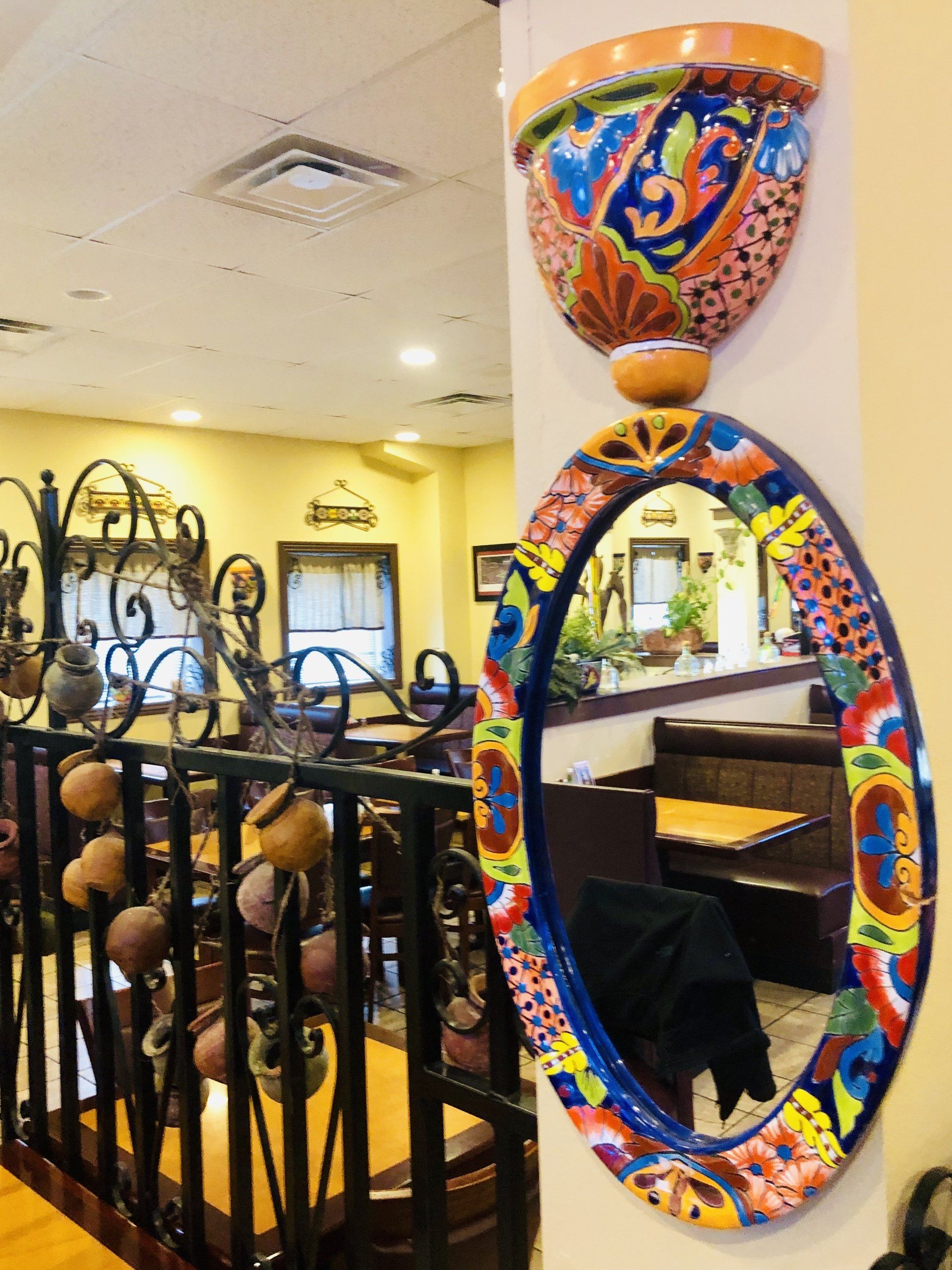 A colorful mirror is hanging on a wall in a restaurant