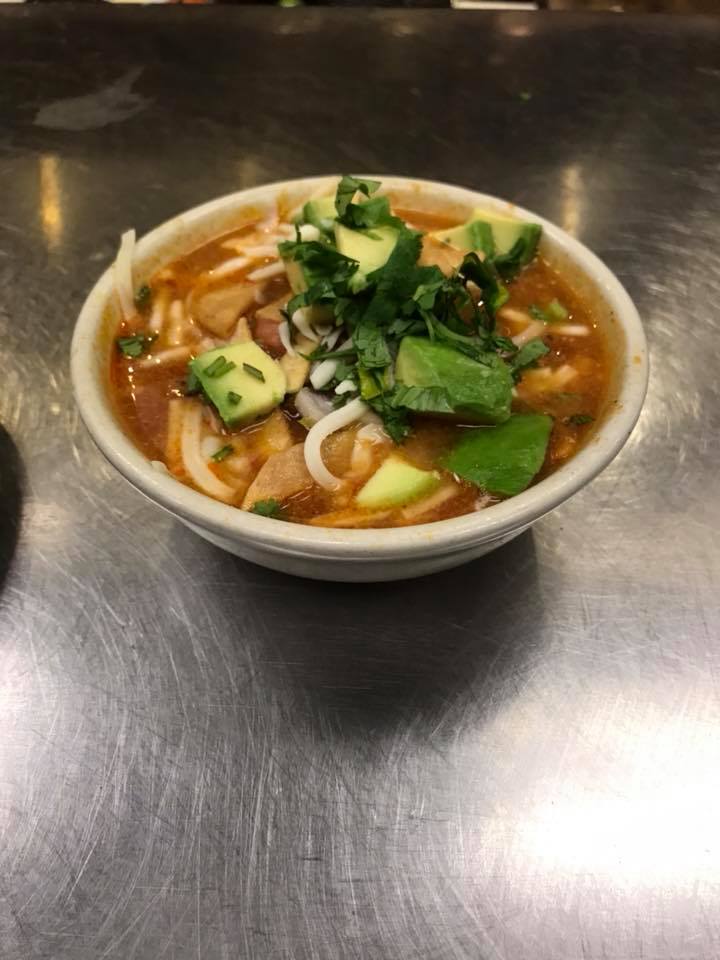 A bowl of soup with noodles and vegetables on a table.