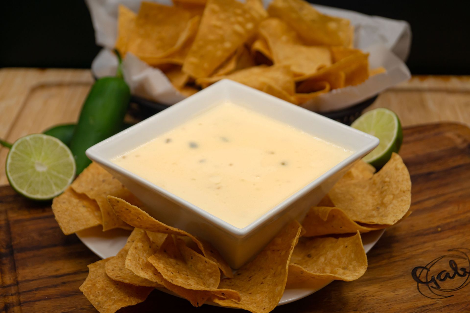 Cheese dip is sitting on top of a plate of tortilla chips.