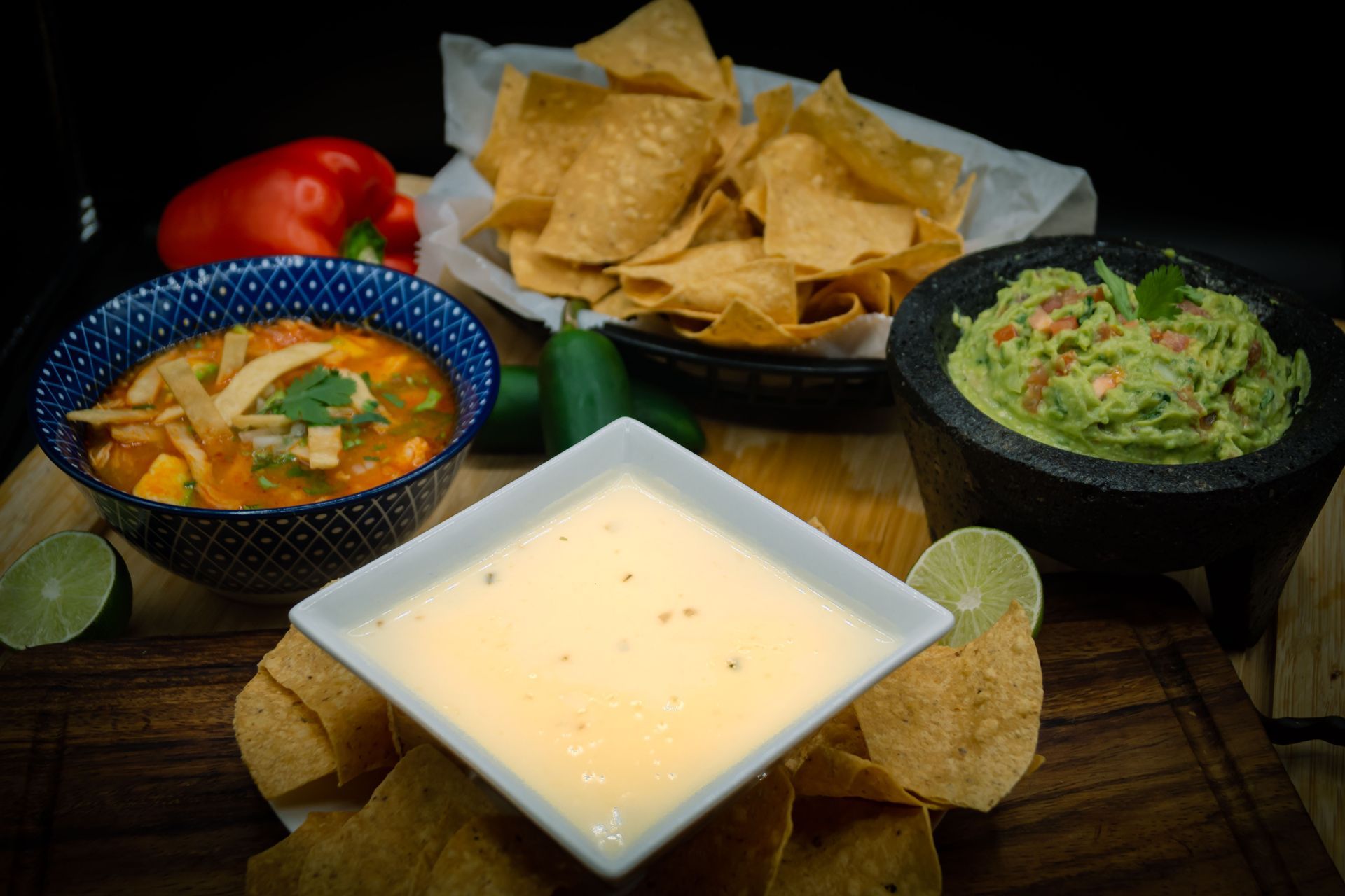 A red plate topped with nachos , guacamole , sour cream and salsa.