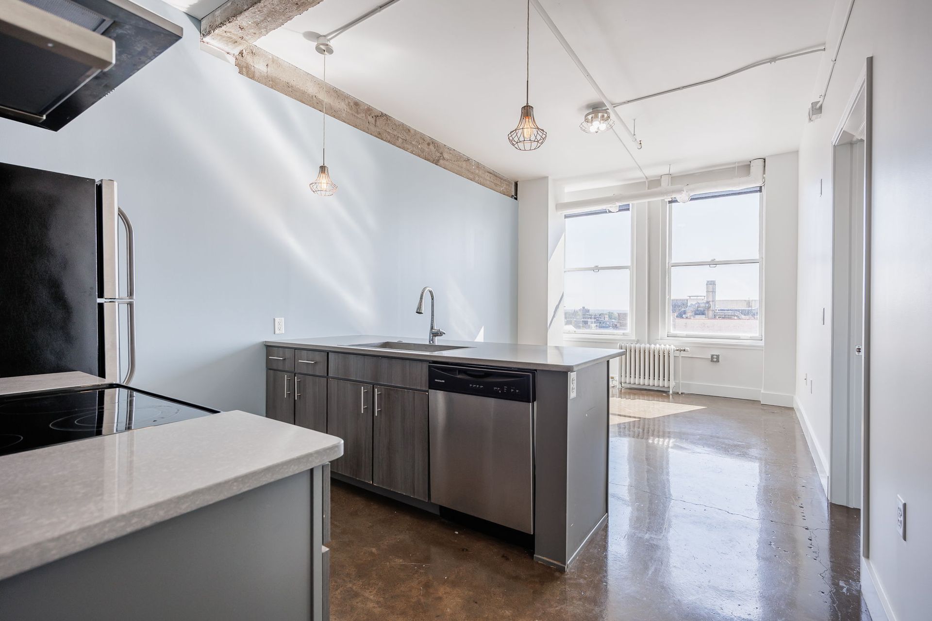 Kitchen opening up to living room with two large windows