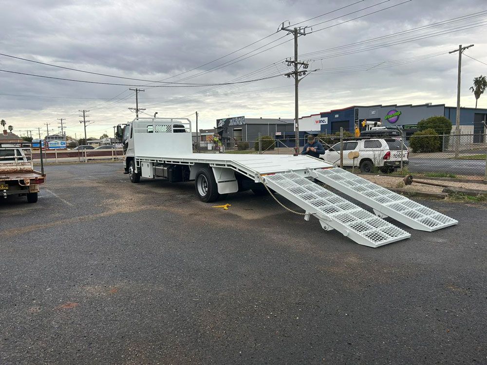A Flatbed Truck with Ramps Attached to It Is Parked in A Parking Lot — EJF Welding in Dubbo, NSW