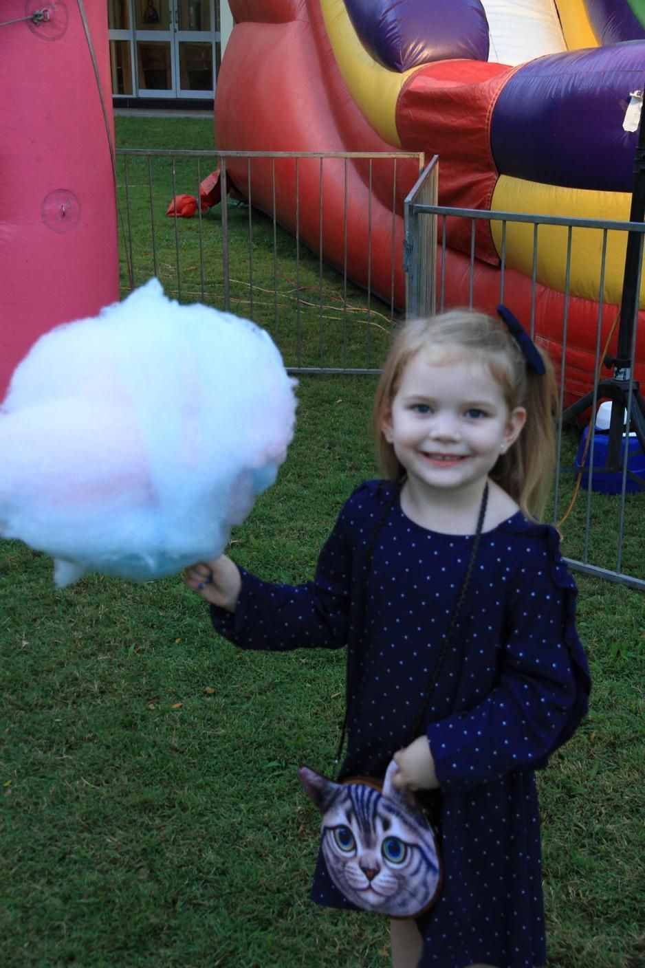 A Little Girl Is Holding Cotton Candy And A Cat Purse — Rides N Slides In Townsville, QLD