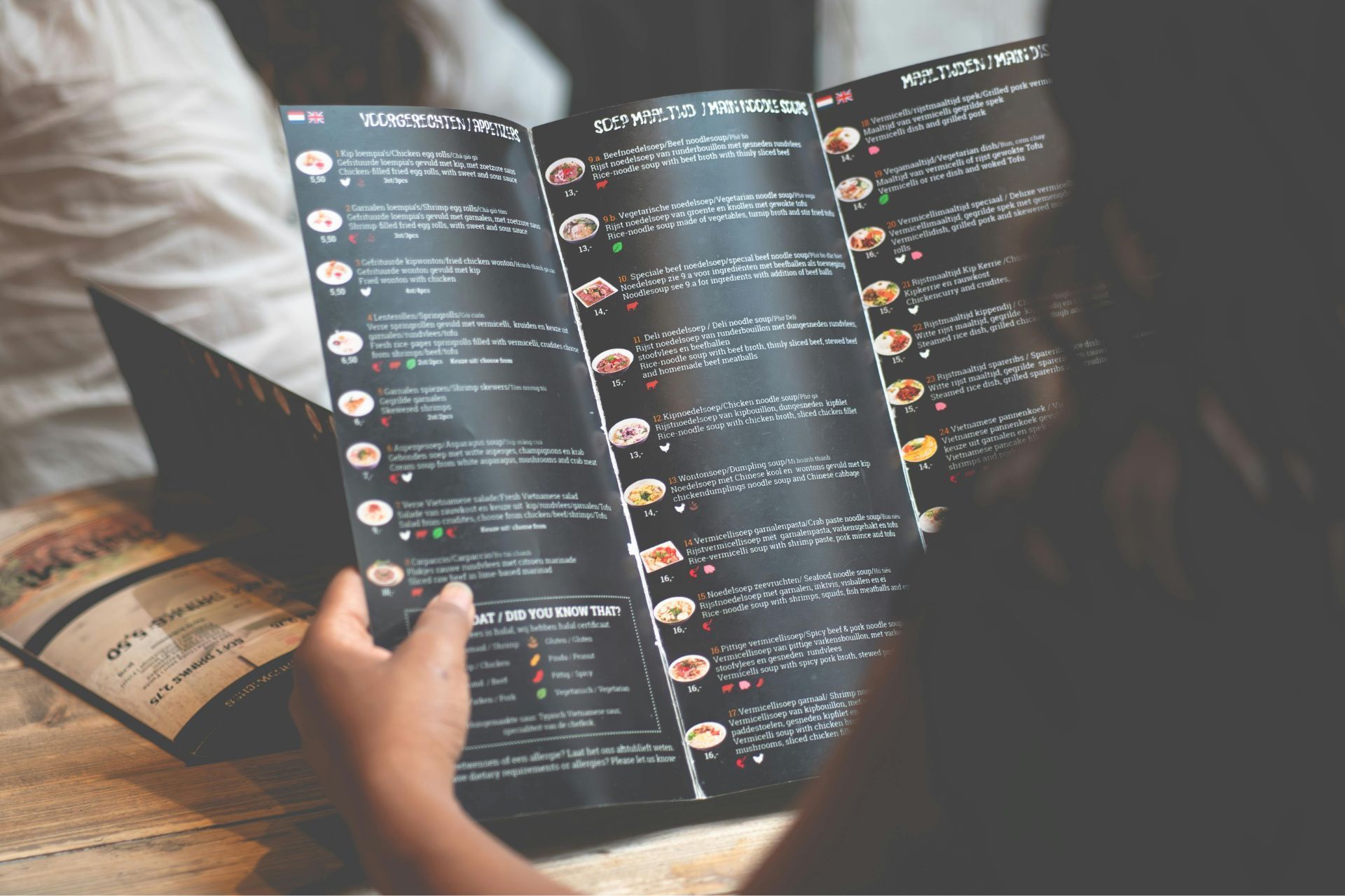 Person holding a restaurant menu, looking at the food options.