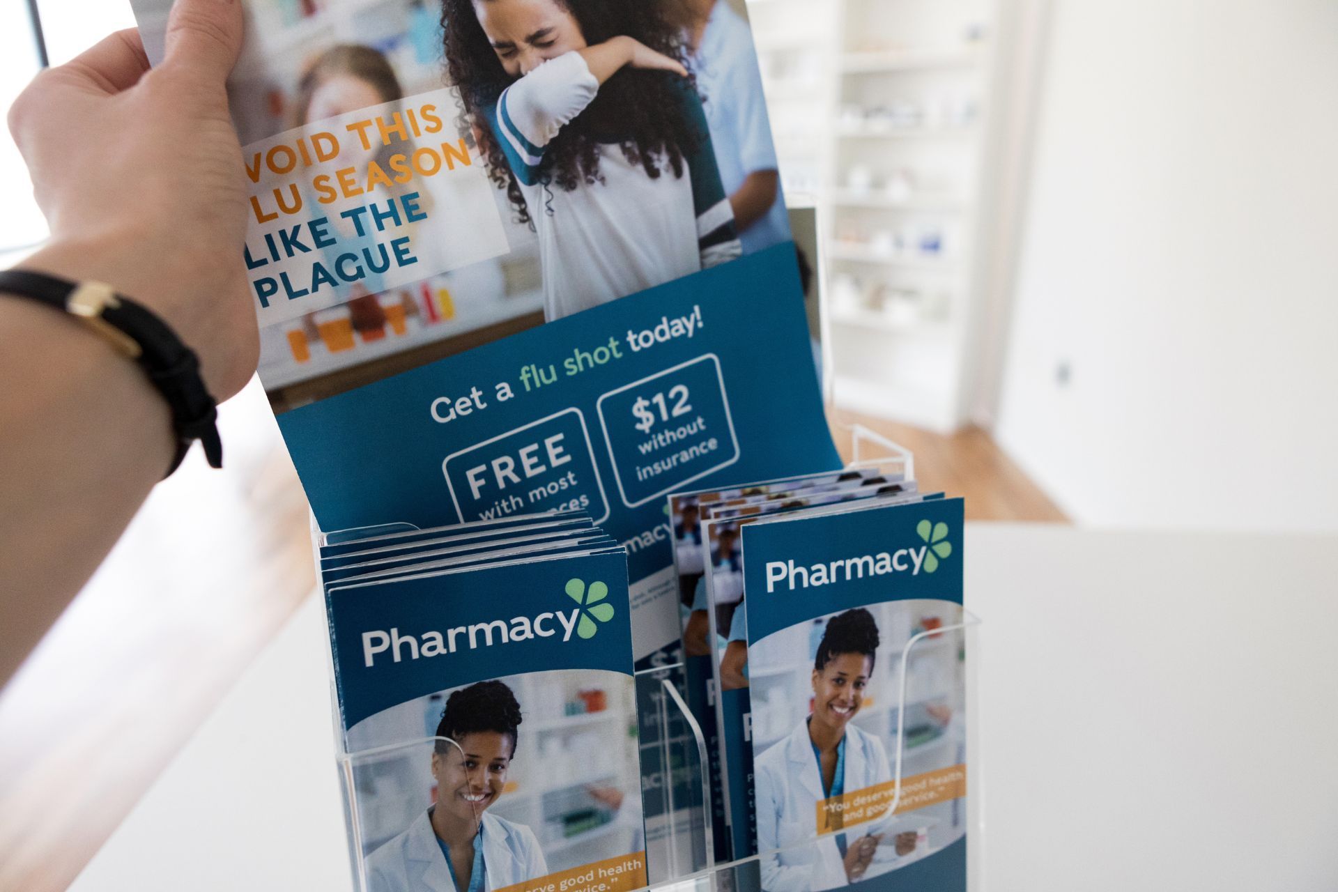 Hand holding a pharmacy flu shot brochure. Displays 