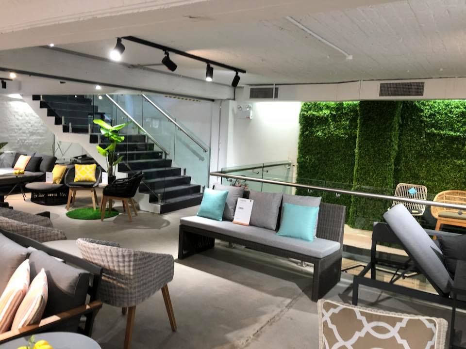 Modern lounge showroom with sofas, chairs, staircase, and green wall decor — ClearView Glass Pool Fencing In Roselands, NSW