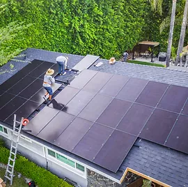 A group of people are installing solar panels on the roof of a house.