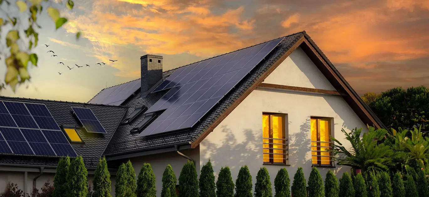 A house with solar panels on the roof at sunset.