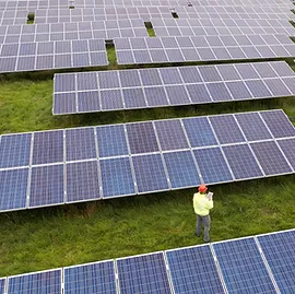 A man is standing in front of a row of solar panels.