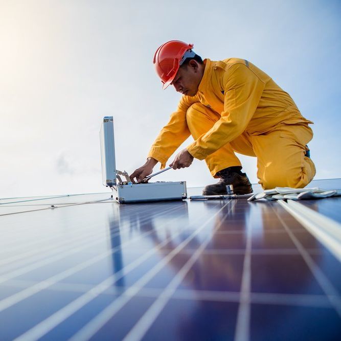 A man wearing a hard hat is working on a solar panel