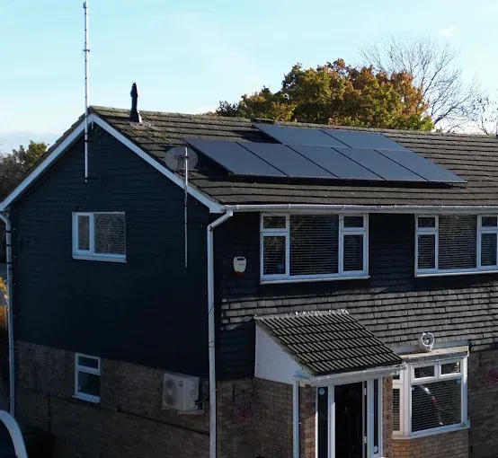 Two-story house with solar panels on the roof, blue siding, and white windows.