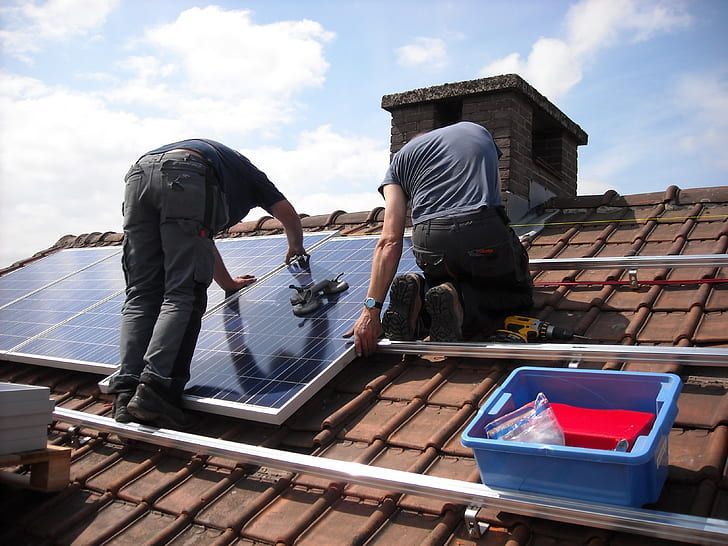 Two men are installing solar panels on a roof