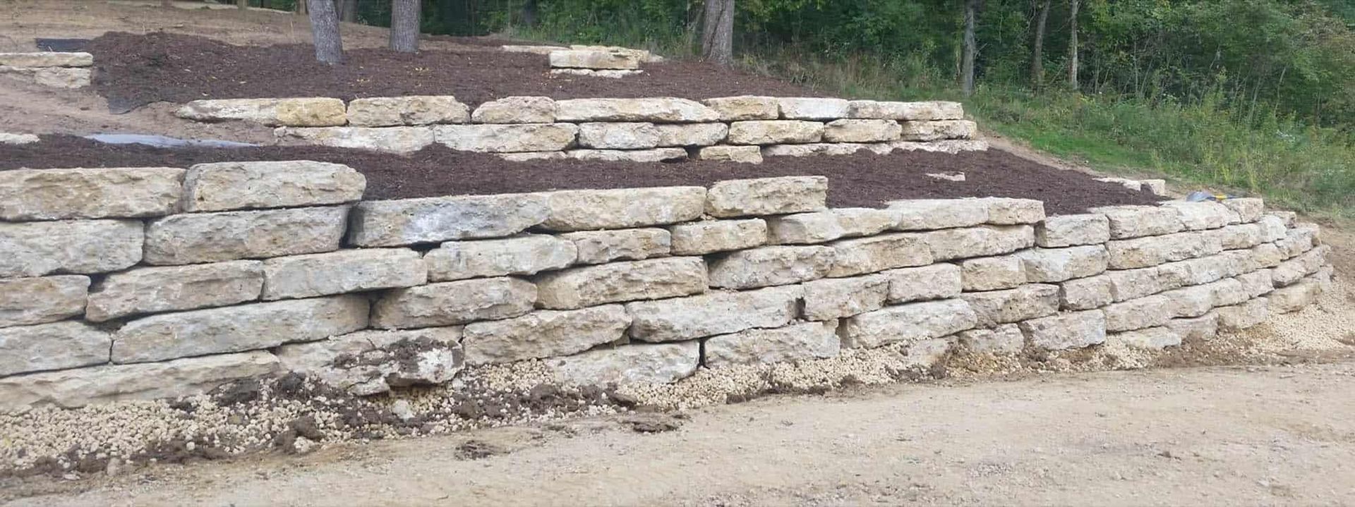 A large stone wall is sitting on top of a dirt hill.
